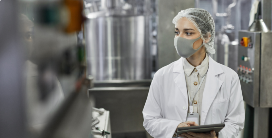 Masked woman working in food factory quality assurance